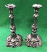 A large pair of 19th Century embossed white metal sheathed table candlesticks on shaped square