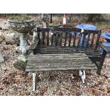 A slatted wooden garden bench seat and a slatted wooden table on painted metal scroll supports,