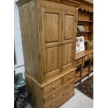 A modern pine wardrobe with two cupboard doors over two short and two long drawers