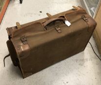 An early 20th Century Asprey leather covered suitcase with canvas outer cover bearing initials