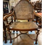 A pair of early 20th Century walnut elbow chairs with bergere back and seat with the legs united by