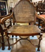 A pair of early 20th Century walnut elbow chairs with bergere back and seat with the legs united by