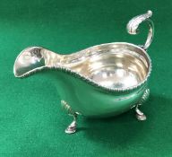 A late Victorian silver sauceboat of inverted helmet form with gadrooned rim on shell decorated