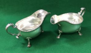 A pair of George V silver sauceboats of inverted helmet form with gadrooned rim raised on three