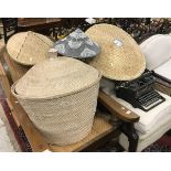 A cane work lidded basket together with three caned hats of small proportion and a larger hat,