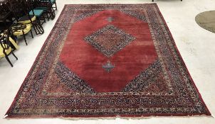 A large Persian carpet with central floral decorated medallion on a plum ground, within a plum,