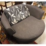 A modern grey upholstered swivel armchair of oversized proportions