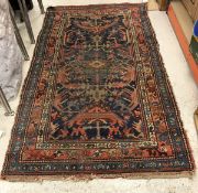 A Caucasian rug, the central panel set with stylised floral decoration on a dark blue ground,