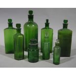 Eight green glass pharmacy flask shape bottles with stoppers,