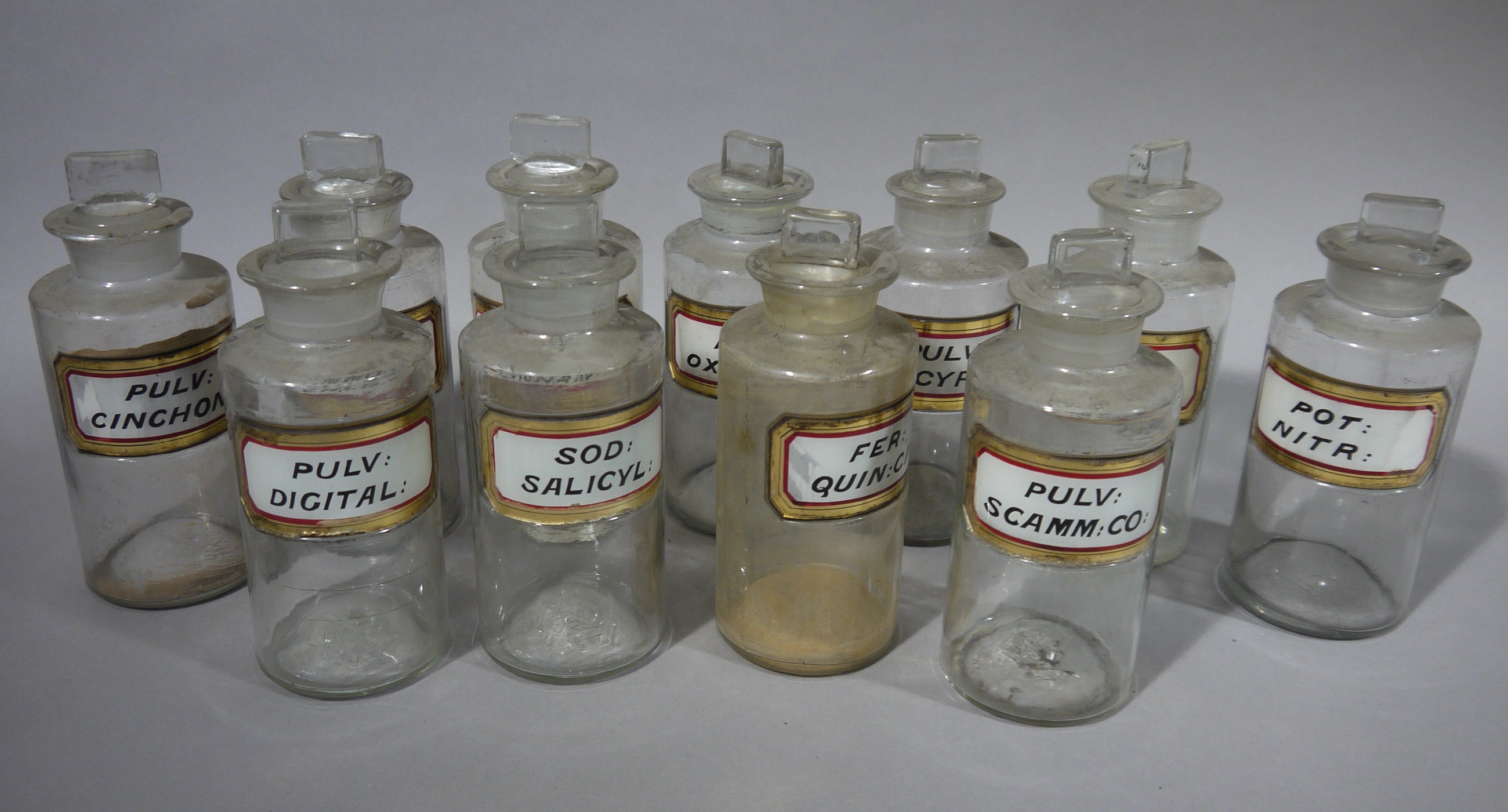 A set of eleven late 19th/early 20th century clear glass pharmacy bottles, cylindrical,