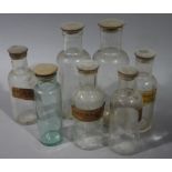 Seven treen disc lidded clear glass pharmacy bottles, various sizes,