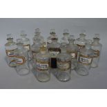 A near set of fourteen late 19th/early 20th century clear glass pharmacy bottles, cylindrical,