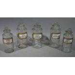 A set of three and a similar pair of late 19th/early 20th century clear glass pharmacy bottles,