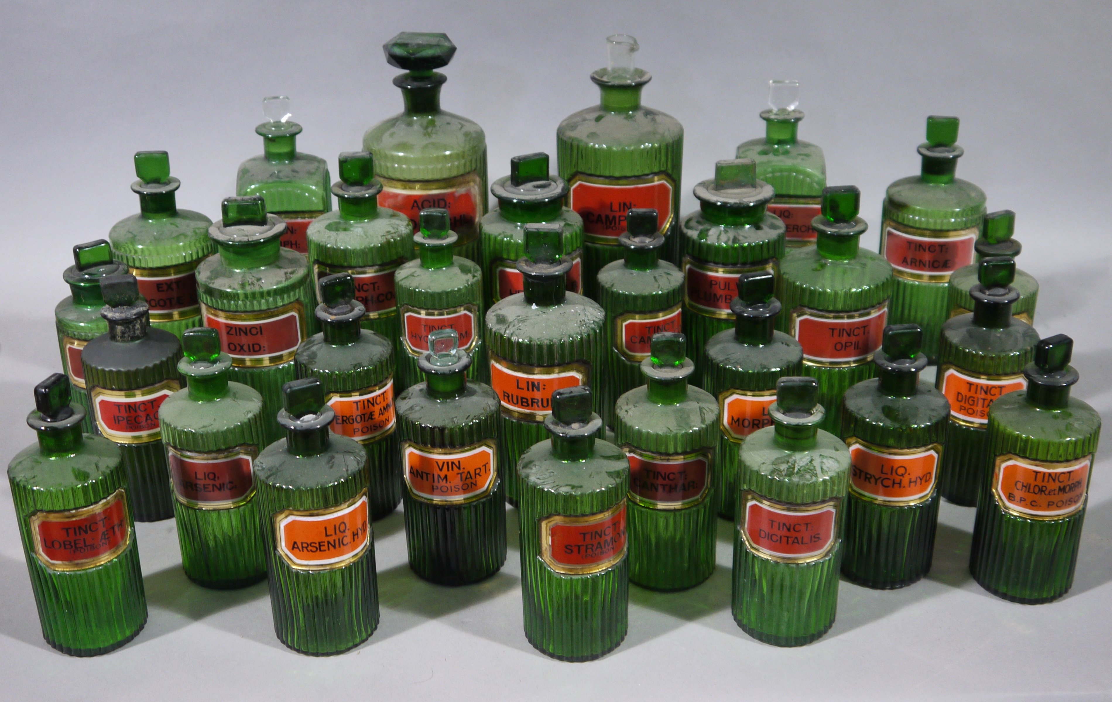 A set of twenty-nine late 19th/early 20th century green ribbed glass pharmacy bottles, cylindrical,