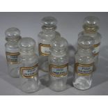 A set of six late 19th/early 20th century clear glass pharmacy bottles in two sizes, cylindrical,