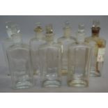 A near set of seven clear glass pharmacy bottles, flask shape with square stoppers,