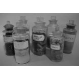 Seven late 19th/early 20th century clear glass pharmacy bottles with square stoppers,