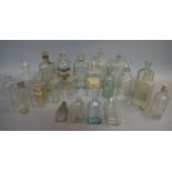 A collection of pharmacy bottles in clear glass, mainly of flask and cylindrical form,