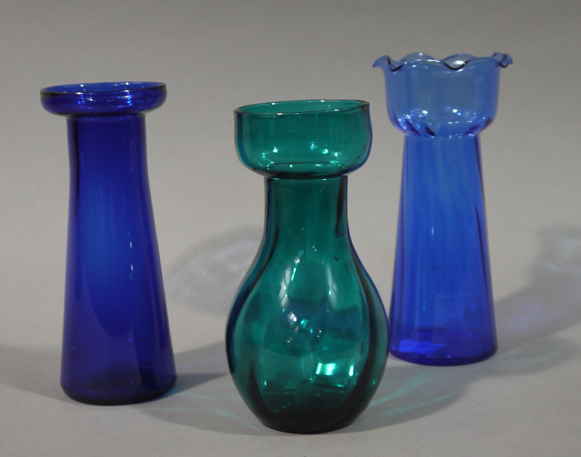 Three glass hyacinth vases in blue and green, 18.5cm, 19.5cm and 17.