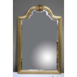 A gilt framed wall mirror of arched outline with foliate cresting and bevelled glass,