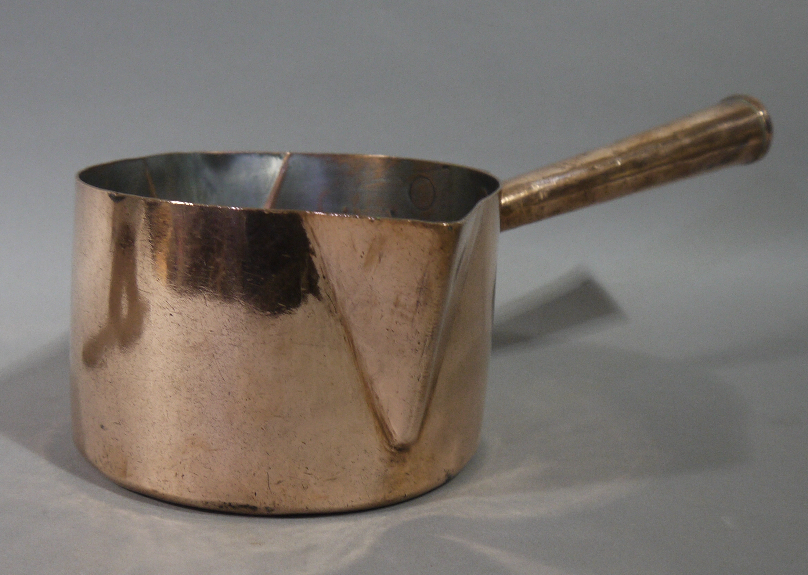 A Victorian double lipped copper saucepan with tapered cylindrical handle,