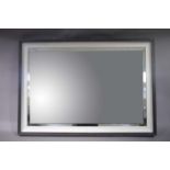 A large bevelled mirror in a cream and dark grey frame,