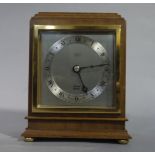 An Elliott walnut mantel clock of square stepped outline with brass bezel and bun feet,