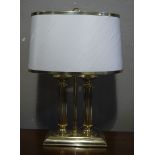 A brass table lamp of double columnar form with central post and ring carrying handle and brass