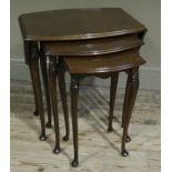 A nest of three walnut occasional tables, the largest with drop leaves of quatrefoil outline,