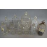 Ten clear glass pharmacy bottles, four of flask form, six cylindrical in two sizes,