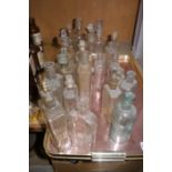 A collection of pharmacy bottles in clear glass, mainly of flask and cylindrical form,