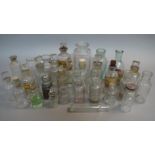 A collection of small pharmacy bottles in clear glass, cylindrical,