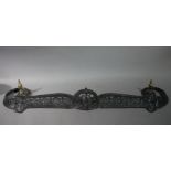 A Victorian cast iron fire kerb of pierced and scrolled design with brass urnular finials