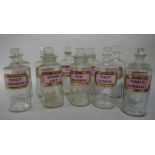 A set of seven late 19th/early 20th century clear glass pharmacy bottles, cylindrical,