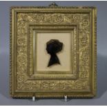 Head and shoulder ink silhouette of a young woman contained within an ornate Victorian gilt wood