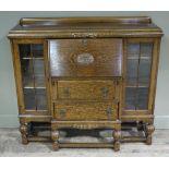 A 1930s/40s oak side by side bureau bookcase having a fall front with carved front with carved boss