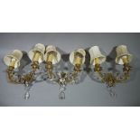 A set of three brass, two branch wall lights with cream shades,