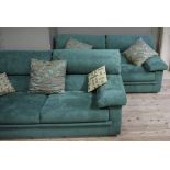 A pair of green suede two seater sofas,