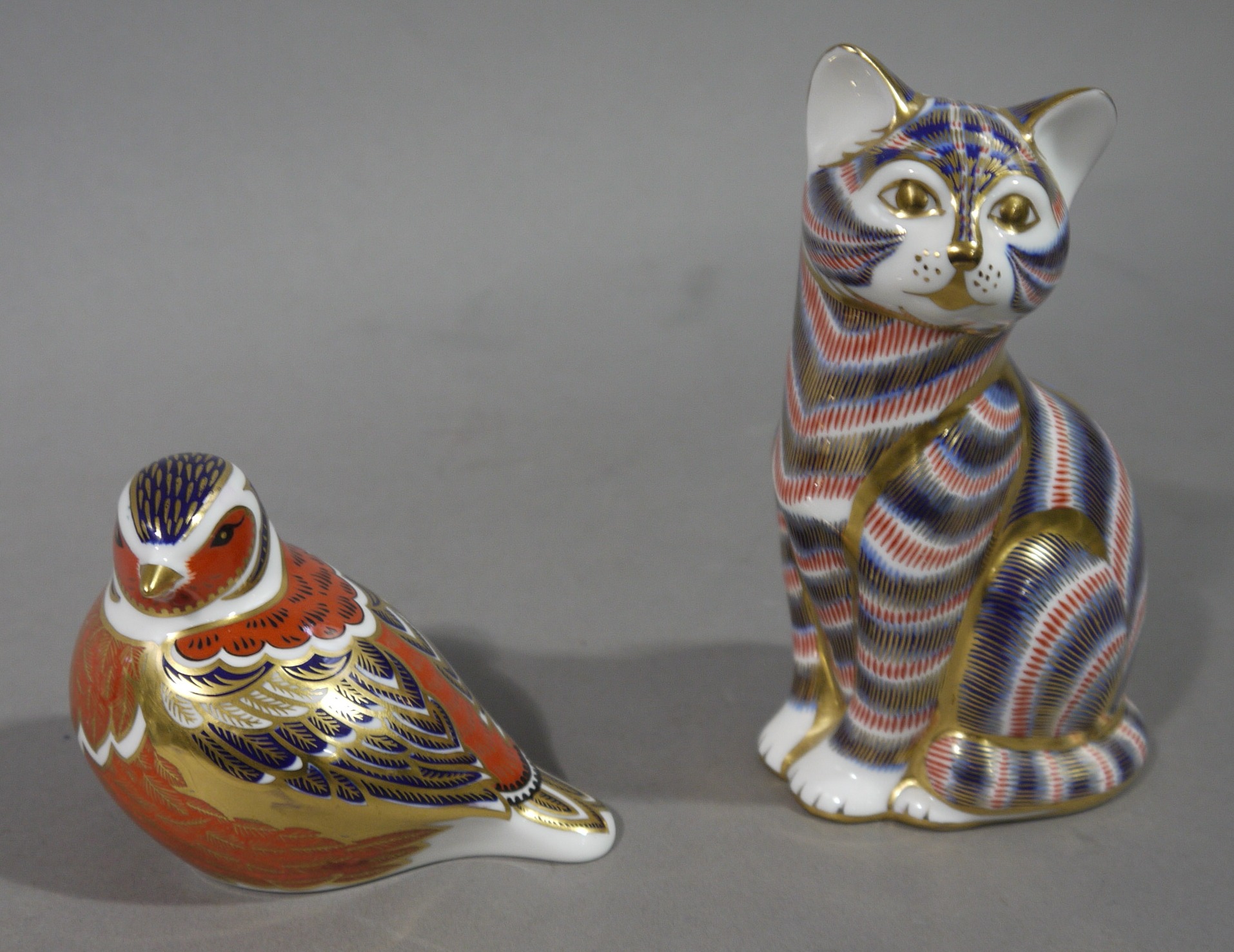 Two Royal Crown Derby paperweights in the form of a cat, and of a bird,