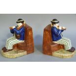 A pair of Quimper pottery bookends modelled as pair of seated figures playing pipes and flute,