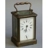 A late 19th century lacquered brass cased carriage clock with swing handle the white dial with