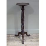 A mahogany tripod torchere with circular top and spiral fluted leaf carved column,