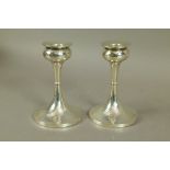 A pair of Arts & Crafts style hammered textured table candlesticks with circular drop pans above