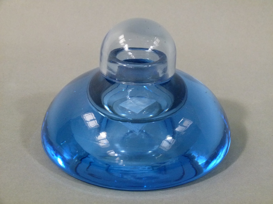 A pale blue glass inkwell of compressed sack form with shallow well and domed loose cover,