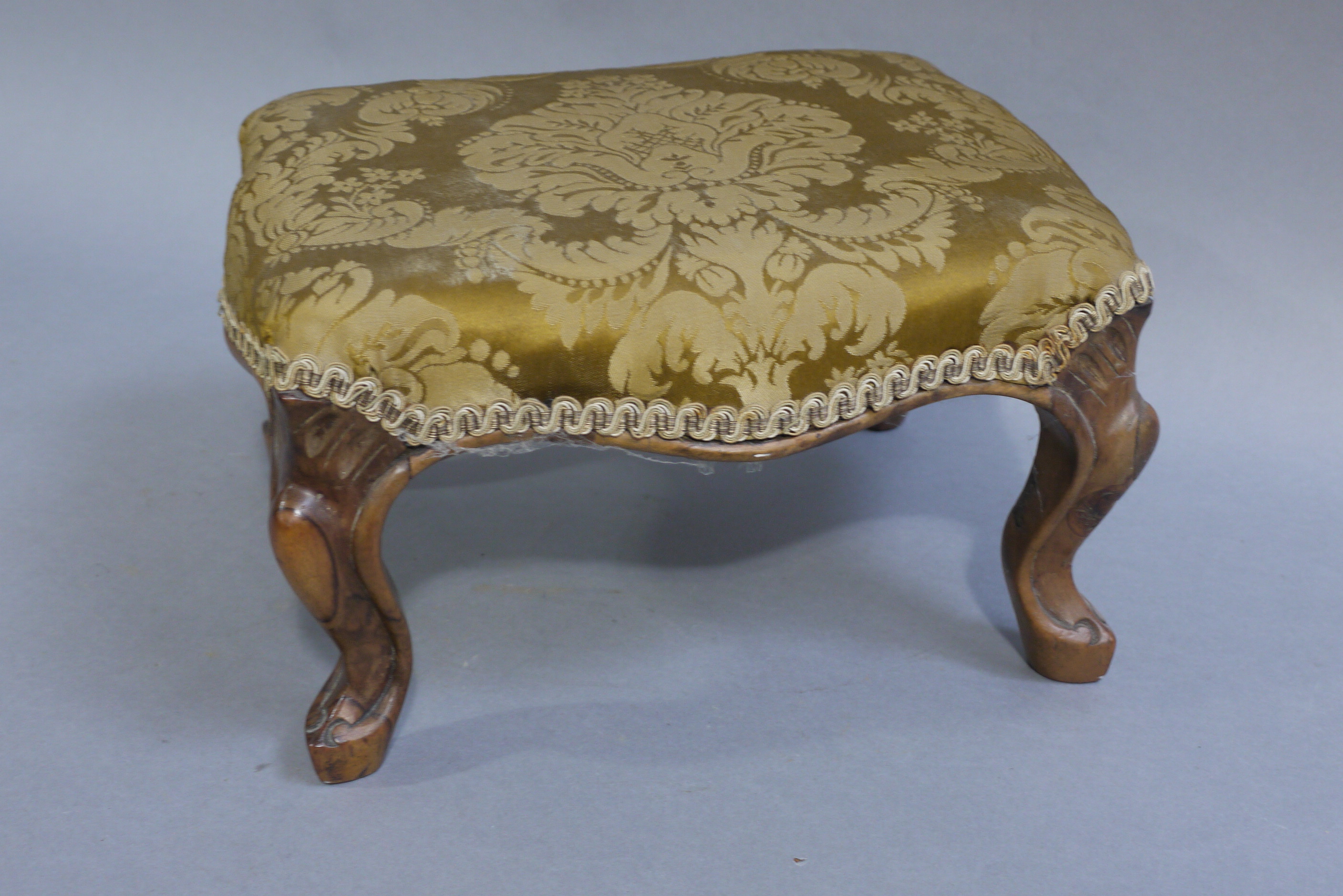 A Victorian walnut footstool of a rectangular outline on cabriole legs