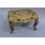 A Victorian walnut footstool of a rectangular outline on cabriole legs