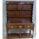 A reproduction oak dresser in 18th century style the planked back with flared cornice,