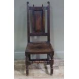 A late 17th century oak chair with panelled back, pair of uprights terminating in scrolls,