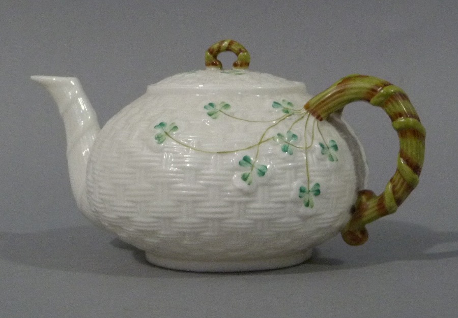 A Belleek basket weave compressed globular teapot decorated with clover leaves,