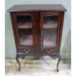 A late Victorian mahogany wall cabinet enclosed by a pair of shaped, glazed doors,